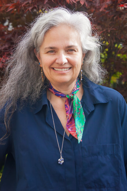 Woman with gray hair wearing a colorful scarf and blue shirt outdoors